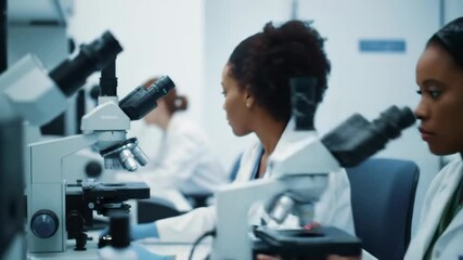 medical research facility. scientific equipment and african american researchers in lab coats. ongoing fight and hope for breakthroughs on world lung cancer day. scientist using microscopes. - Powered by Adobe