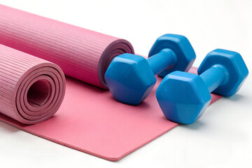 Blue dumbbells on a pink yoga mat for fitness and workout.