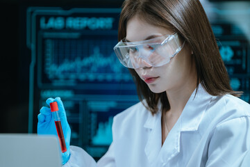 A scientist in a laboratory conducts a medical experiment with a red liquid in a test tube,...