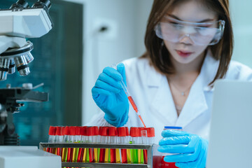 A scientist in a laboratory conducts a medical experiment with a red liquid in a test tube,...