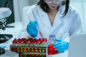 A scientist in a laboratory conducts a medical experiment with a red liquid in a test tube,...