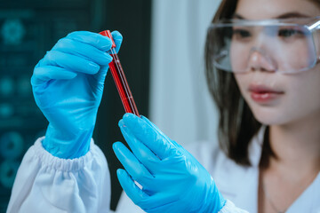 A scientist in a laboratory conducts a medical experiment with a red liquid in a test tube,...