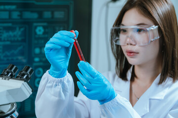 A scientist in a laboratory conducts a medical experiment with a red liquid in a test tube,...