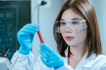 A scientist in a laboratory conducts a medical experiment with a red liquid in a test tube,...