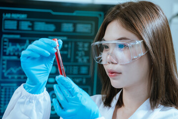 A scientist in a laboratory conducts a medical experiment with a red liquid in a test tube,...