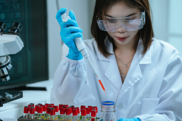 A scientist in a laboratory conducts a medical experiment with a red liquid in a test tube,...