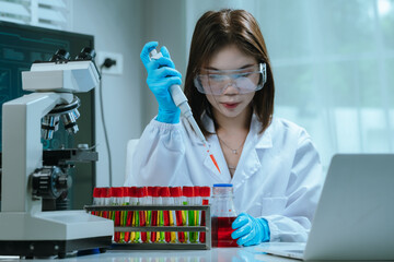 A scientist in a laboratory conducts a medical experiment with a red liquid in a test tube,...