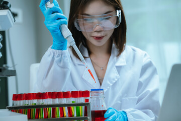 A scientist in a laboratory conducts a medical experiment with a red liquid in a test tube,...