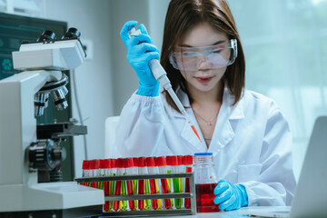 A scientist in a laboratory conducts a medical experiment with a red liquid in a test tube,...
