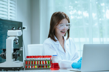 A scientist in a laboratory conducts a medical experiment with a red liquid in a test tube,...