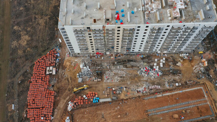 Construction progress on a multi-story residential building with materials in the foreground