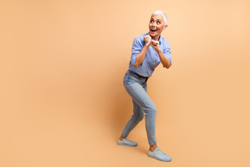 Elderly woman wearing a stylish casual outfit posing on a beige background with expressive gestures and a happy mood