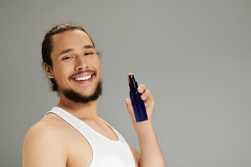 Handsome young man showcasing grooming product with a joyful expression in a minimalist setting
