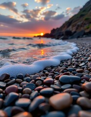 Fototapeta premium Sunset Over Ocean Waves Gently Washing Onto Pebbled Beach with Colorful Stones