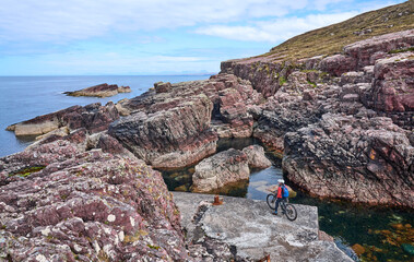 active senior woman riding her electric mountain bike on the cliffs near Rua Reidh Lighthouse next...