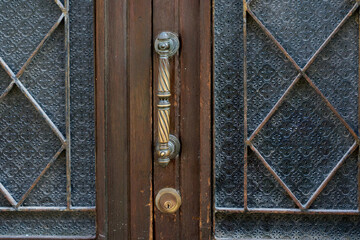 Old ornate brass door handle and textured glass window panes