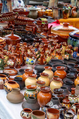 Colorful handmade ceramic pots and mugs on display at a street market. Traditional pottery in various shapes, sizes, and patterns.
