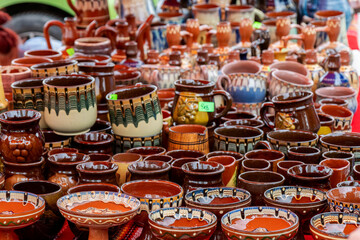Colorful handmade ceramic pots and mugs on display at a street market. Traditional pottery in various shapes, sizes, and patterns.