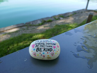 Kindness rock with be kind message on wet table with water's edge out of focus