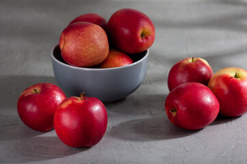Fresh red apples in a bowl on gray surface