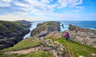 active senior woman riding her electric mountain bike at Strathy  point lighthouse in Northern...