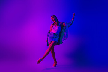 Lovely Young Woman Dancing in Neon Purple and Blue Light Showcasing Style and Energy