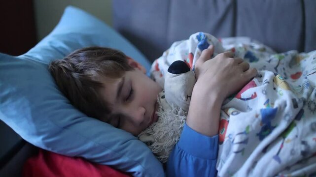 A teenager is lying in bed hugging a teddy bear. insomnia
