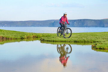 active senior woman riding her electric mountain bike at the coast of  Strathy point  Northern...