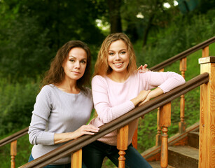 Beautiful mother and adult daughter, two generations. Summer day in the park.