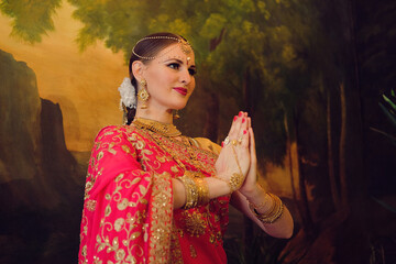Young woman in red sari, traditional Indian bride, hands folded, namaste