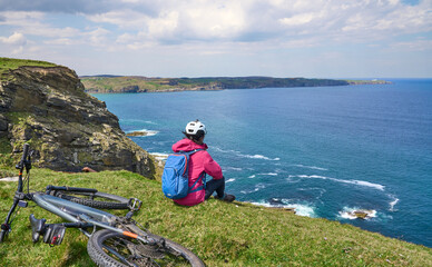 active senior woman riding her electric mountain bike on the cliffs of Strathy  point lighthouse in...