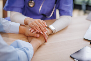 Compassionate Asian Nurse Offering Comfort by Connecting Hands at a Healthcare Facility 

