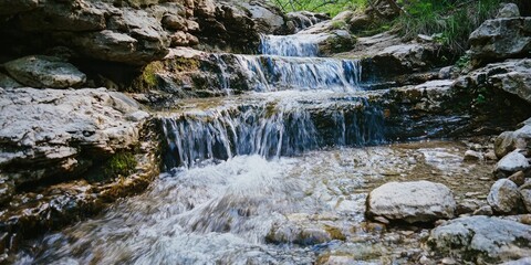A narrow waterfall flowing gently over smooth stones
