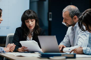 Business executives and assistants brainstorming investment risk evaluation in corporate boardroom