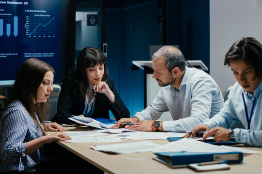 Business executives and assistants brainstorming investment risk evaluation in corporate boardroom