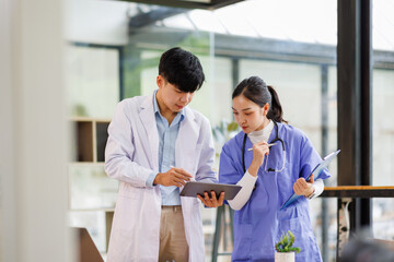 A Female nurse showing something on tablet to Male doctor both smiling in hospital 