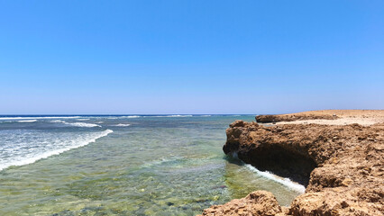 Natural background with sea view with underwater coral reef and rocky shore of Red Sea in Egypt. Clear day, clear blue sky, sunny day. Ideal for summer tourism and recreation.
