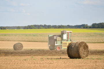 A tractor cleans the field with flax and makes bales