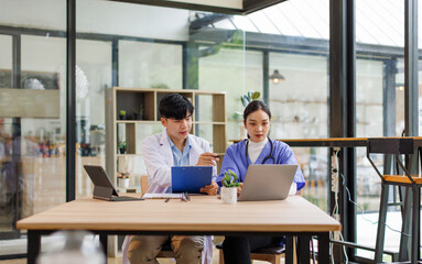 A Doctors and female nurse cooperating while working on laptop in the office.
