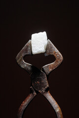 Heart shaped vintage Sugar Cutter with cube of sugar on a black background 