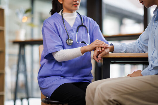 A female nurse hand caregiver holds senior patient's hands, and comfort an elderly. Doctor helping For care senior man and trust in nursing homes
