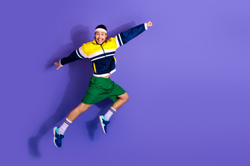 Active energetic man in sportswear jumping against a purple background showcasing active lifestyle...