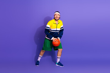 Energetic young man showcasing retro sports style with vibrant outfit and basketball against a...