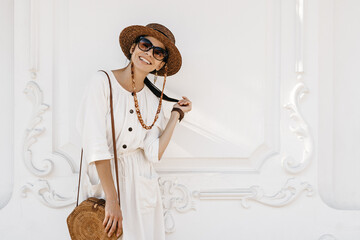 attractive woman walking in city street on vacation dressed in white summer fashion dress