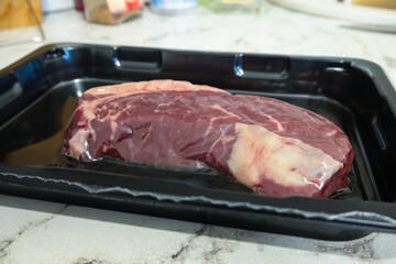 Beef steak in hermetic plastic packaging lies on marble countertop
