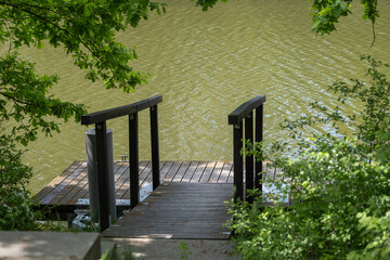 Wooden river dock framed by lush green leaves