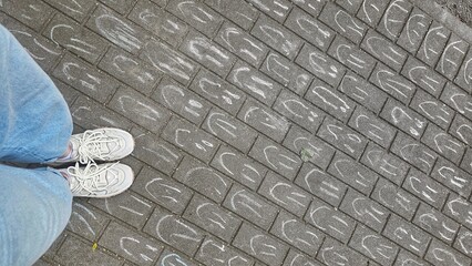 Feet on Chalk‑Drawn Smiles Brick Pavement