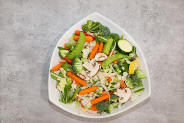 Uncooked stir fry vegetables in a white bowl.