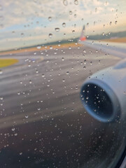 A plane is on the runway with raindrops on the window