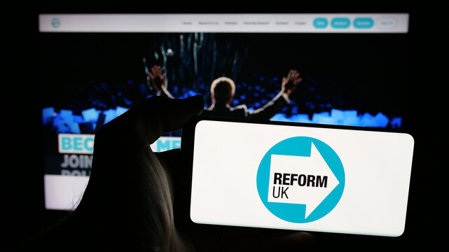 Stuttgart, Germany - 07-09-2025: Person holding mobile phone with logo of British political party Reform UK on screen in front of web page. Focus on phone display.